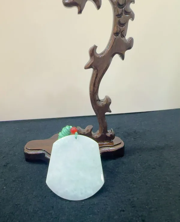 Carved jade pendant on wooden stand