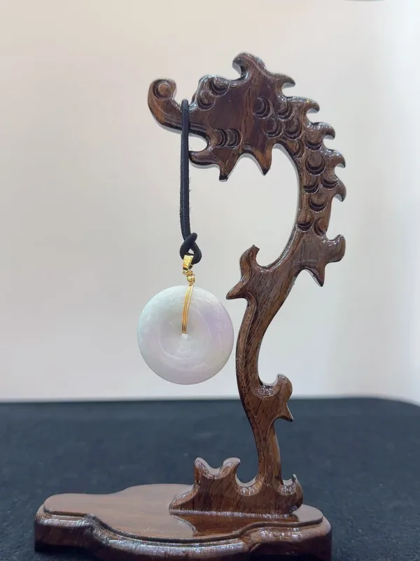 Carved wooden stand holding a spherical stone pendant.