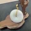 Jade pendant on wooden display stand.