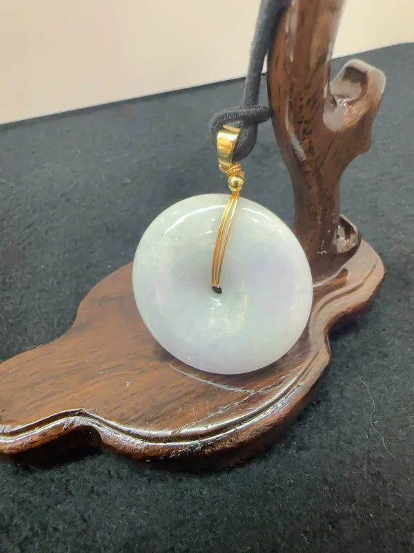 Jade pendant on wooden display stand.