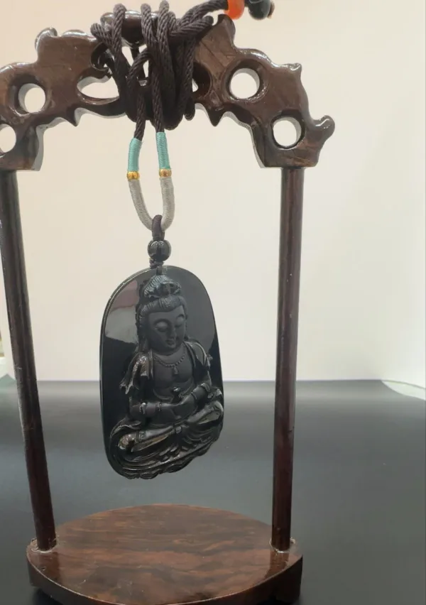 Carved Buddha pendant on wooden stand.