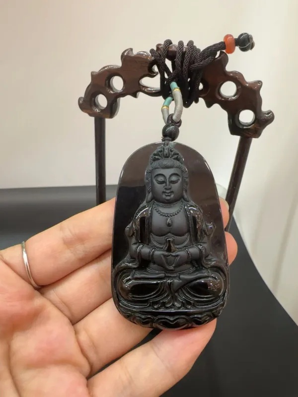 Carved Buddha pendant held in hand.