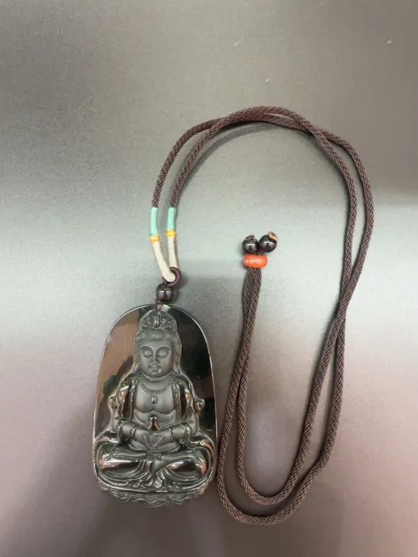 Buddha pendant on braided brown necklace.