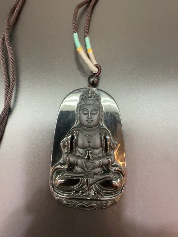 Buddha pendant on necklace with intricate design.