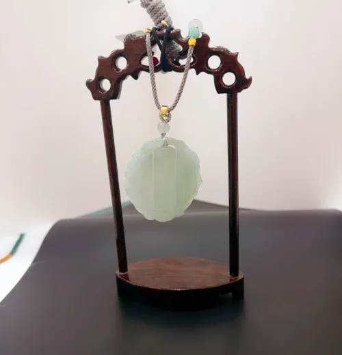 Jade pendant on wooden display stand.