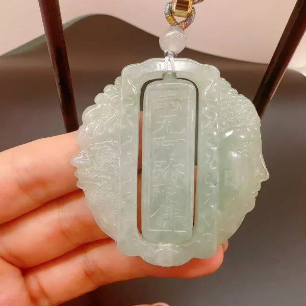 Hand holding carved jade pendant.