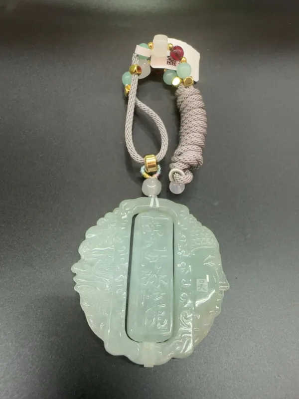Jade pendant with Chinese inscriptions and decorative tassel.