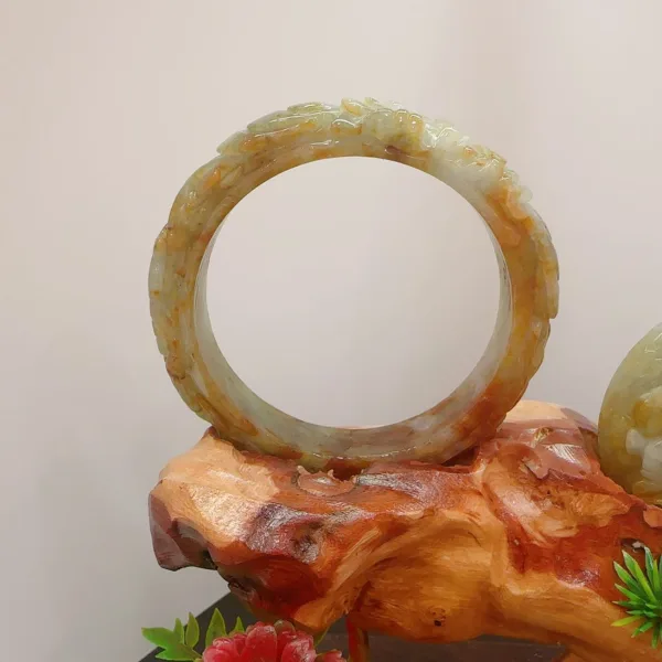 Carved jade bracelet on wooden stand.