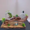 Jade sculpture with peonies and bonsai on wooden base.