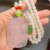 Hand holding carved jade dragon pendant and beads.