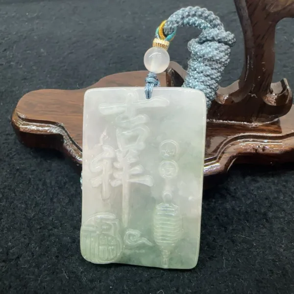 Carved jade pendant with stand and knotted cord.