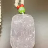 Carved jade pendant with beads on table.