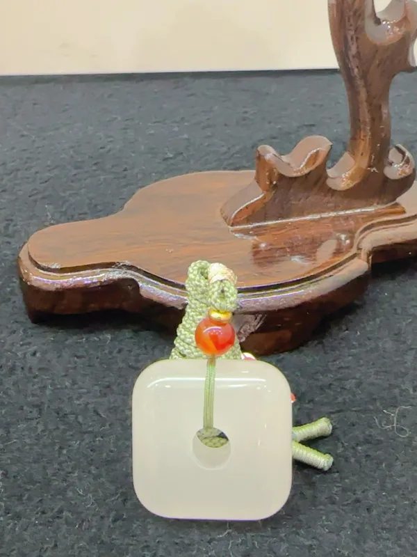 Carved wooden guitar stand with ornamental keychain.