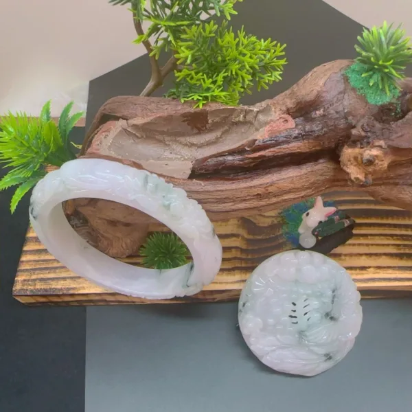 Jade bracelets and figurine on wooden display with plants.