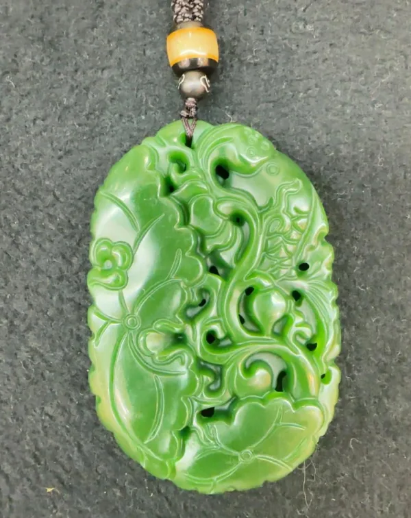 Carved green jade pendant with intricate design.