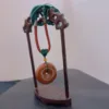 Carved wooden stand displaying a jade pendant.