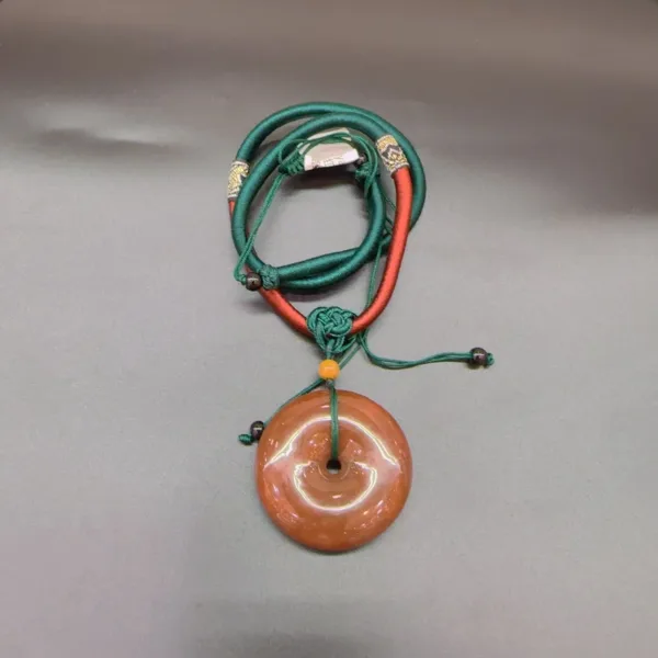 Jade pendant on green and red cords.