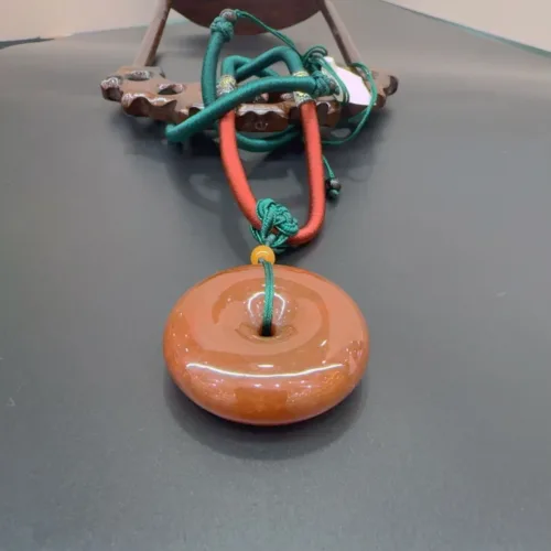Orange donut pendant with green cord.