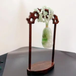 Jade pendant and beads on wooden display stand.