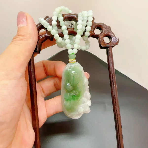 Jade pendant and beads on wooden display stand.