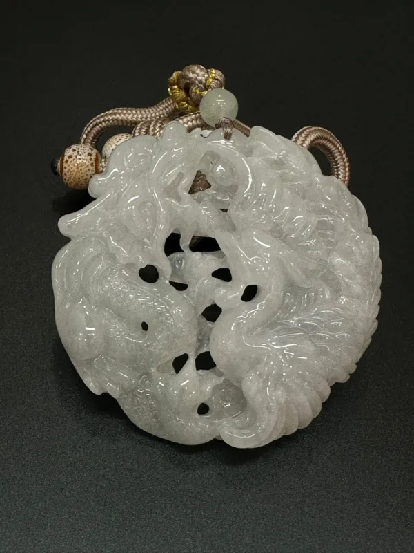 Carved jade pendant with cord on black background.