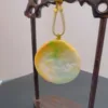 Jade pendant displayed on wooden stand.