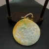 Carved jade pendant on wooden stand.