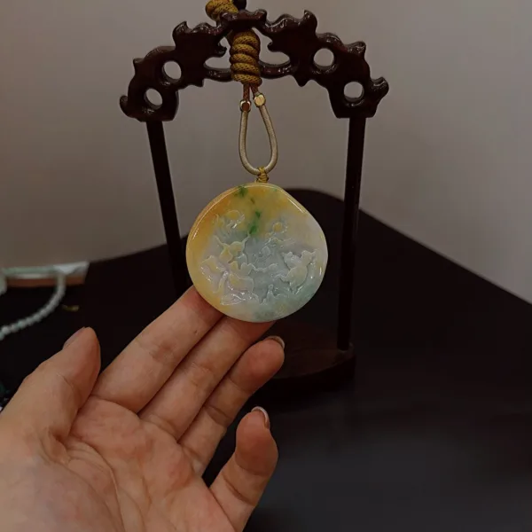 Hand holding a jade pendant on display stand.