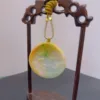 Carved jade pendant displayed on wooden stand.