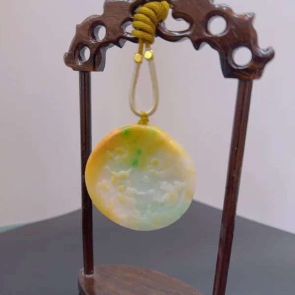 Carved jade pendant displayed on wooden stand.