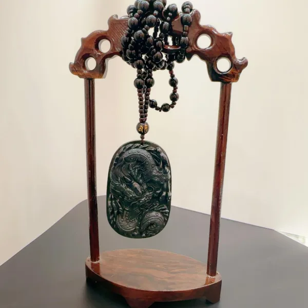 Carved jade pendant on wooden stand with beads.
