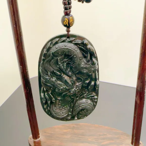 Carved jade dragon pendant on wooden stand.
