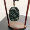 Carved jade dragon pendant on wooden stand.