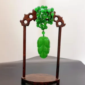 Green jade cicada sculpture on wooden stand.