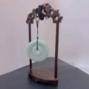 Carved wood stand displaying jade disc.