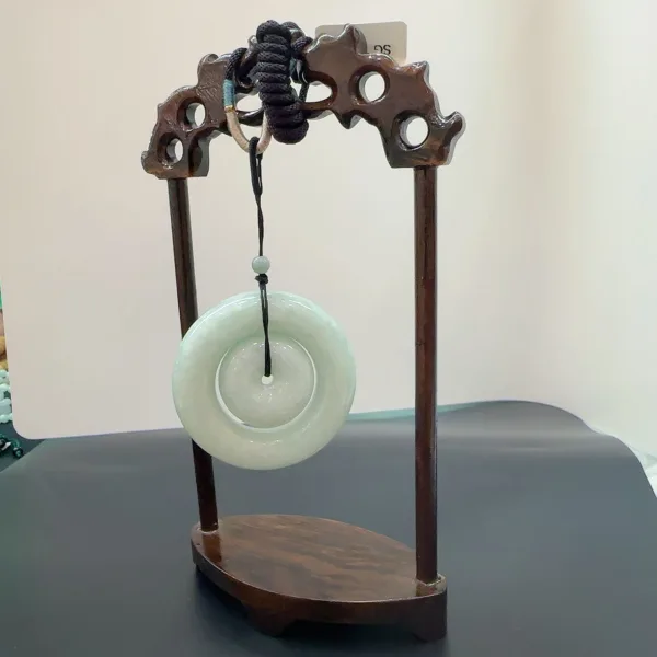 Carved wooden stand displaying circular jade disc.