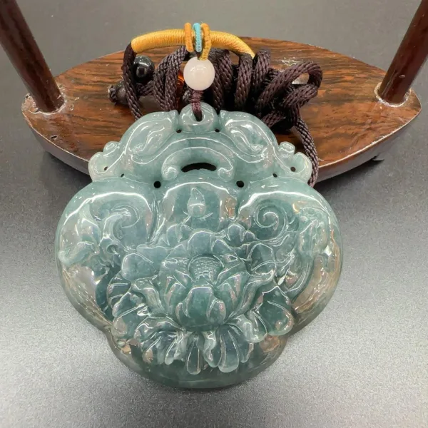 Carved jade pendant with lotus design on display.