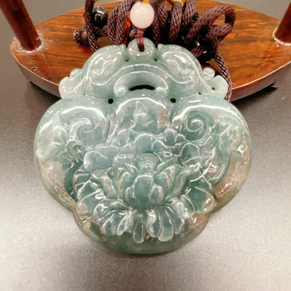 Carved jade pendant with floral design on display.