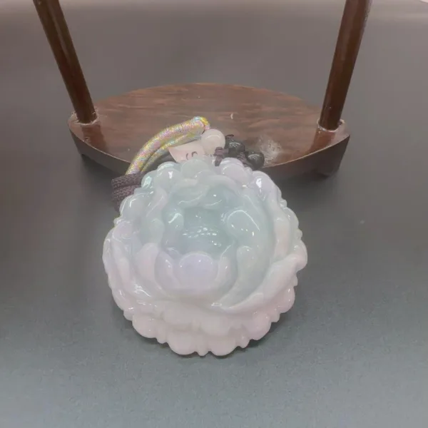 Carved jade flower sculpture on wooden stand.