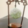 Carved jade pendant on wooden stand.