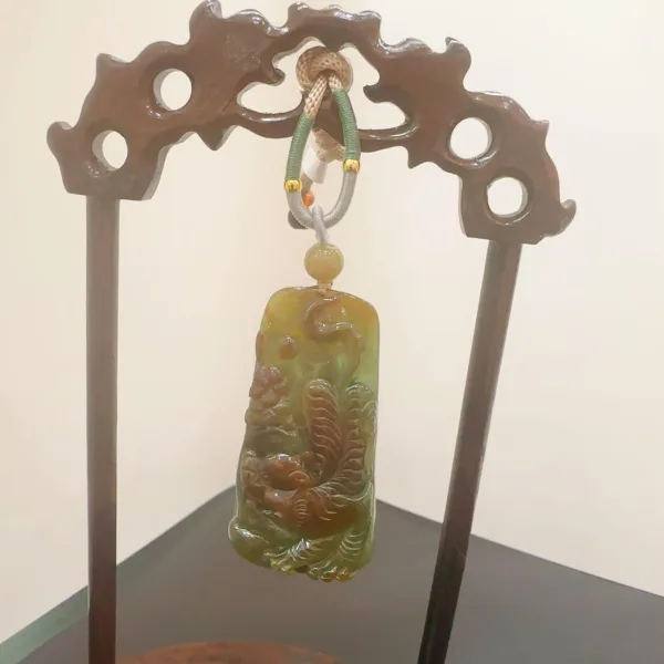 Carved jade pendant with wooden stand.