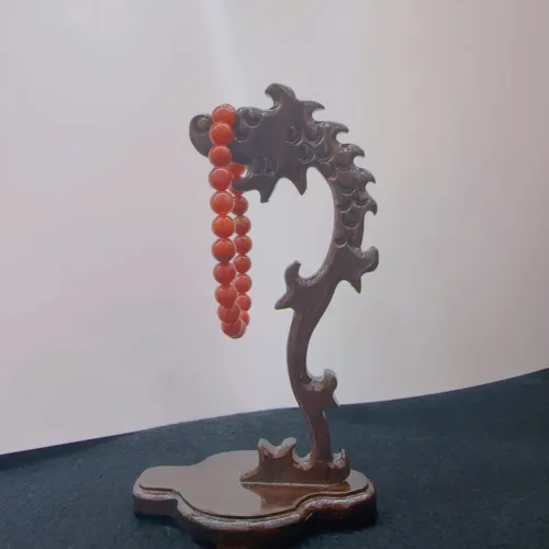 Carved wooden dragon stand with red beads.