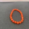 Orange beaded bracelet on gray surface.