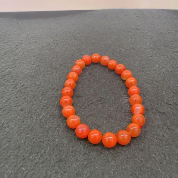 Orange beaded bracelet on gray surface.