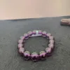 Purple beaded bracelet on gray surface.