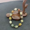 Multi-colored stone bracelet on wooden display stand.