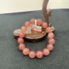 Pink beaded bracelet on wooden display stand.