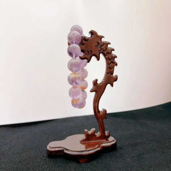 Carved wooden stand holding spherical amethyst crystal balls.