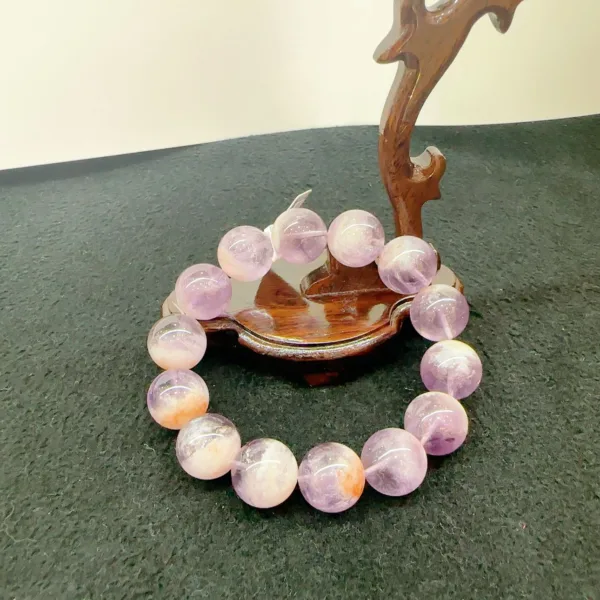 Amethyst crystal bracelet on wooden stand.