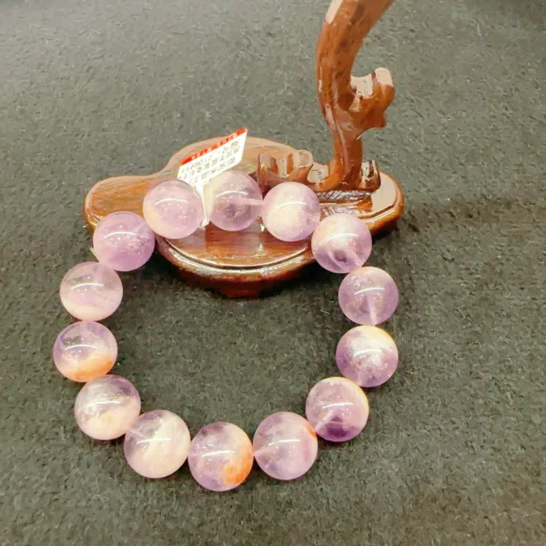 Amethyst bracelet with wooden tree display on gray background.